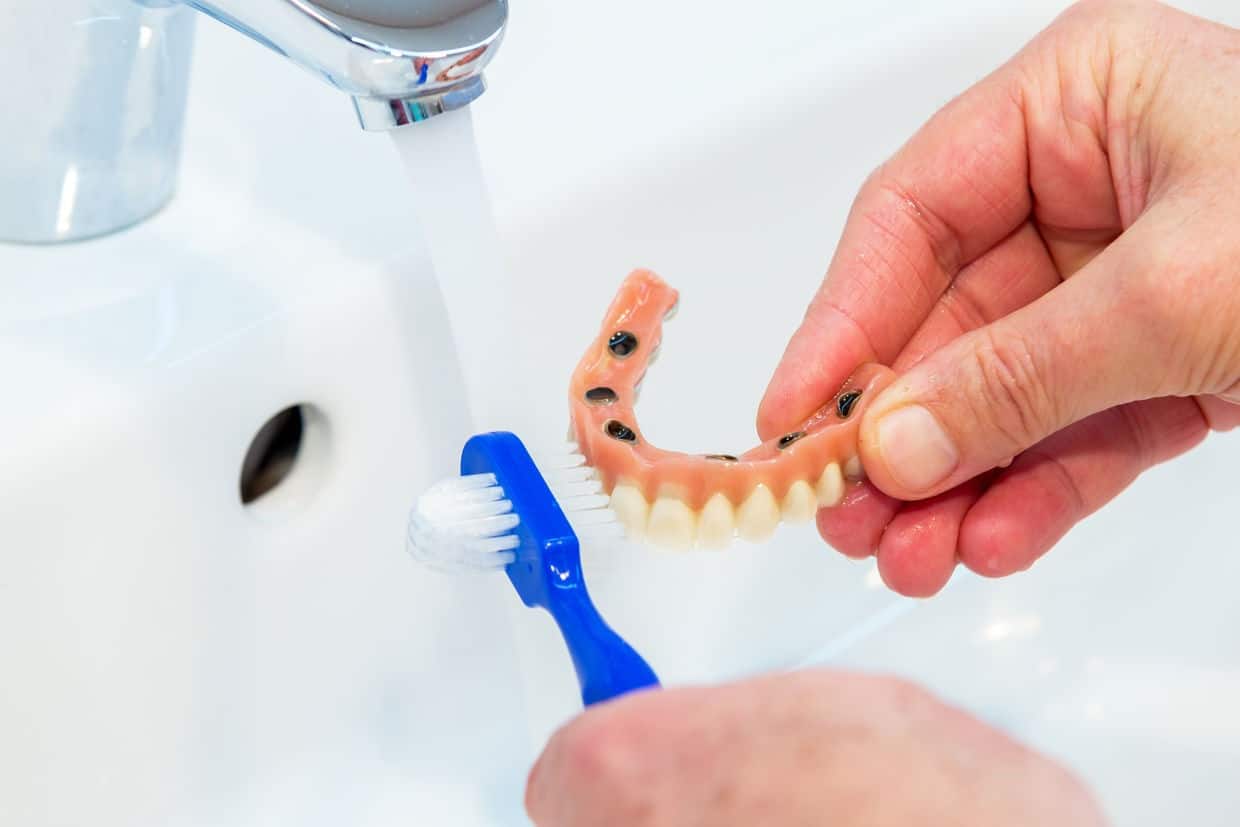Cleaning dentures with a brush