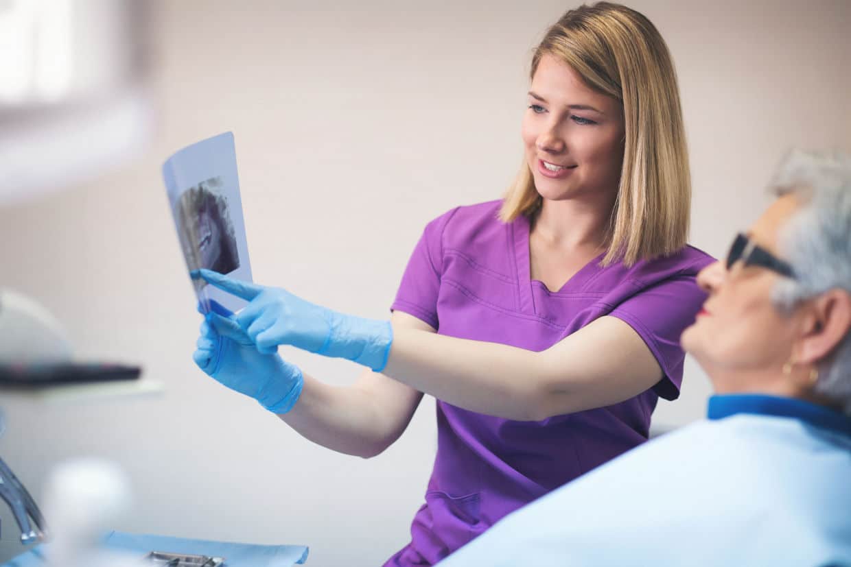 dental implant procedure step by step being explained by dental assistant holding xray